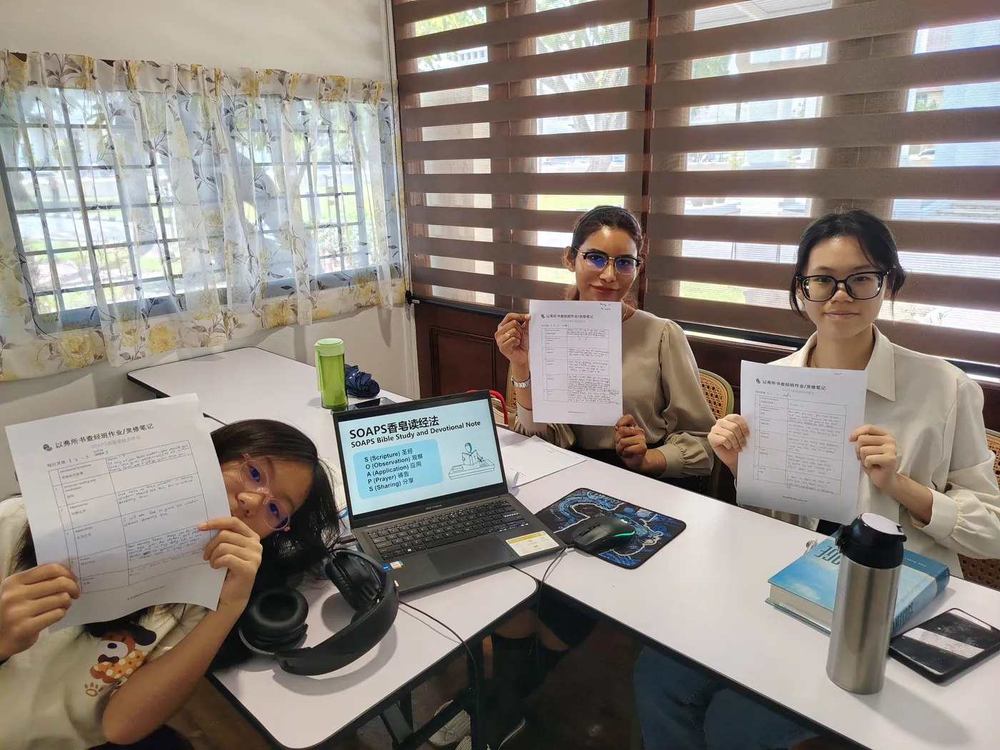 Learners holding up their SOAPS Bible study sheets in class