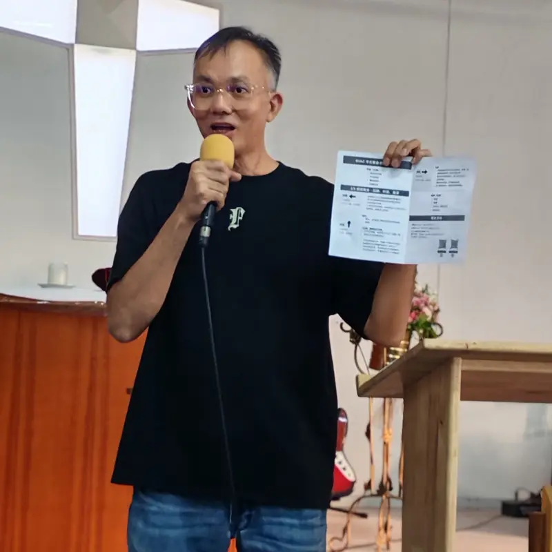 Pastor Jony teaching with a microphone and a handout