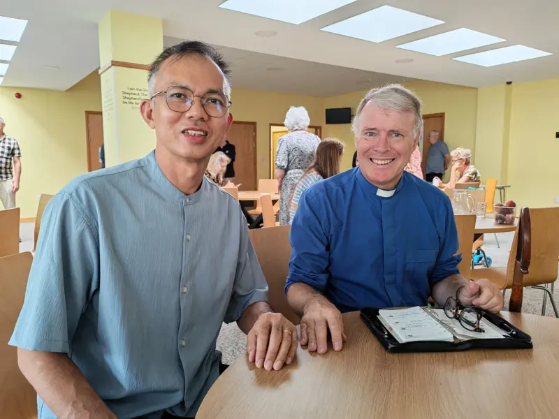 Pastor Jony talking with the vicar of St Luke's over coffee