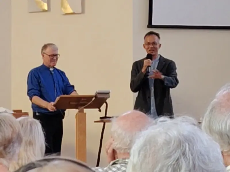 Pastor Jony speaking at St Luke's Church, Watford, beside the vicar