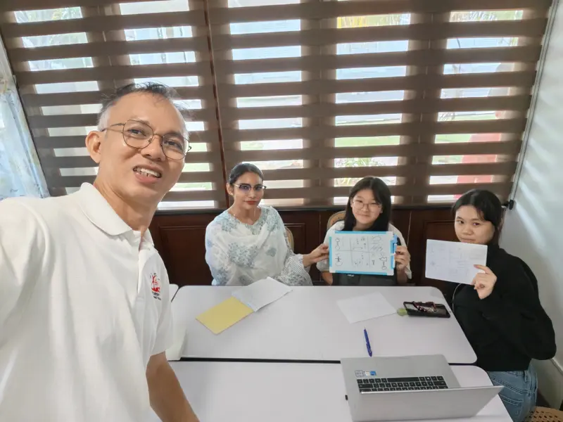 Pastor Jony with three women holding up their Zúme training sheets at a café table